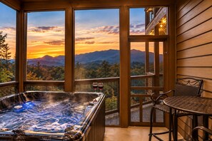 Ein Whirlpool auf einem Balkon mit Blick auf Berge und einen Sonnenuntergang.