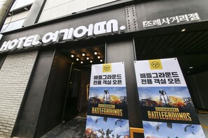 The entrance of a hotel with a sign that reads "HOTEL OTHON." There are two large posters advertising "PlayerUnknown's Battlegrounds." - Hotel Yeogiuhtte Suncheon Jorye (Suncheon)