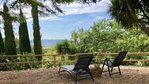 Deux fauteuils noirs sont placés sur une surface de gravier, avec une clôture en bois et des cactus en arrière-plan.