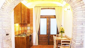 Cuina amb armaris de fusta, terra de rajola i finestra amb cortines.