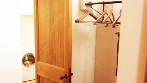 Una porta de fusta que dona a un bany amb rentadora, penjador de tovalloles i prestatgeries metàl·liques.