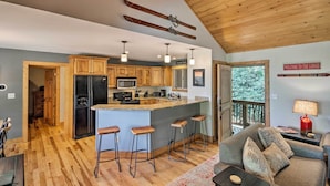 A modern kitchen with wooden cabinets, a central island with bar stools, and a ski rack on the ceiling. - Cabin w/ Fireplace & Mountain Views: 5 Mi to Boone (Blowing Rock)