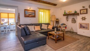 Una sala de estar con un sofá modular, una mesa de centro y una zona de comedor con sillas.