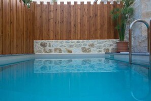 Una piscina con cerca de madera y pared de piedra.