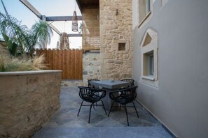 Un patio al aire libre con un muro de piedra, una cerca de madera y una mesa con sillas.