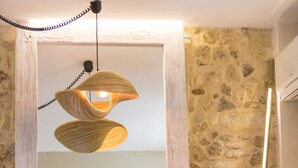 Un intérieur moderne avec une table à manger en bois, une chaise, un luminaire suspendu original et un mur en pierre.