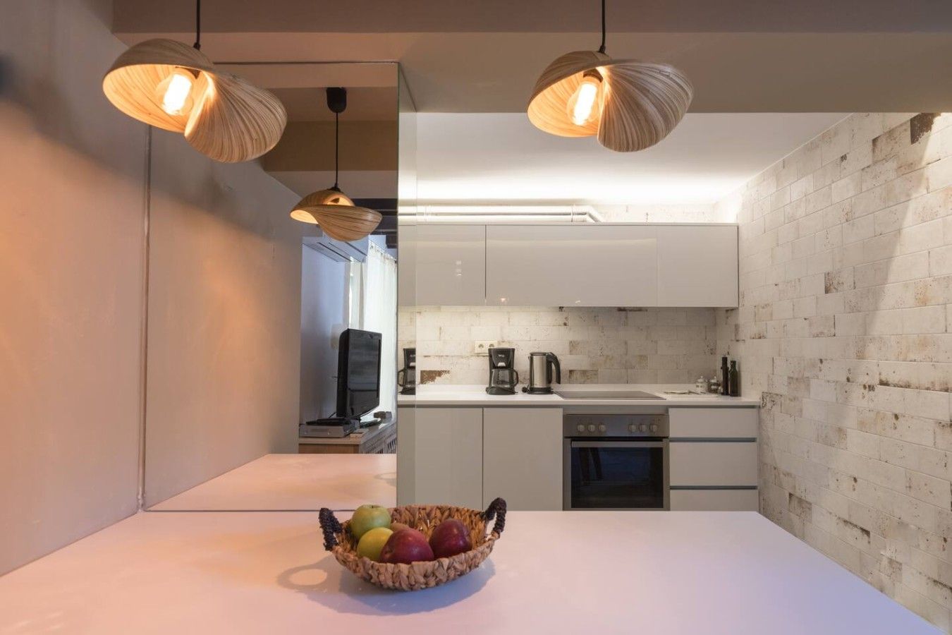 A modern kitchen with white cabinets, a stainless steel oven, and a fruit bowl on the counter.