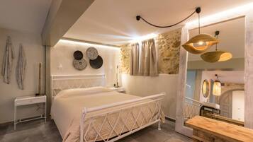 A bedroom with a bed, bedside table, wall decor, and a wooden bench.