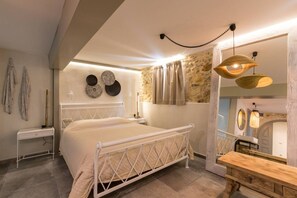 A bedroom with a bed, bedside table, wall decor, and a wooden bench.