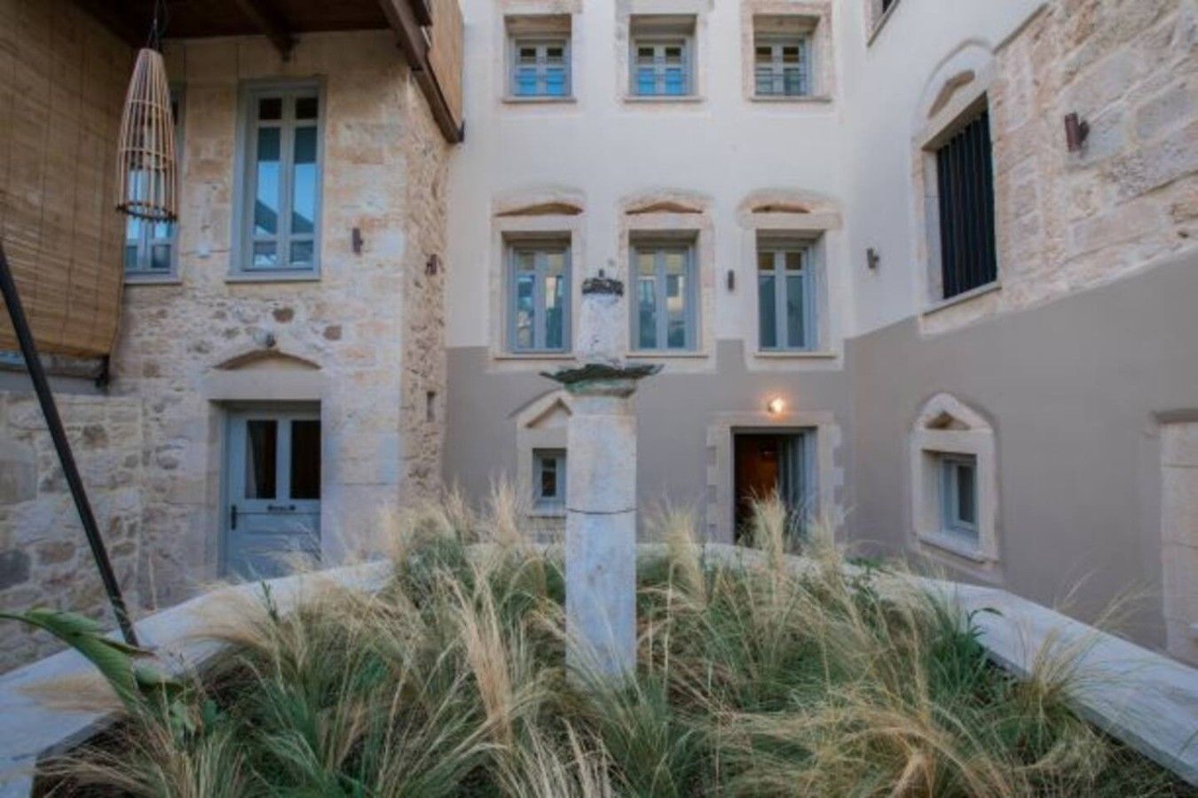A courtyard with a central fountain, stone walls, and multiple windows with shutters.