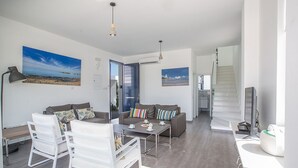 A modern living room with a sofa, coffee table, and chairs, a staircase, and artwork on the walls. - Villa Kylee, Fabulous 5BDR Protaras Villa with private pool, close to the beach (Protaras)