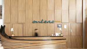 En hotelreception med en væg af træpaneler, et moderne receptionsområde og et skilt der står 'antico HOTEL'.