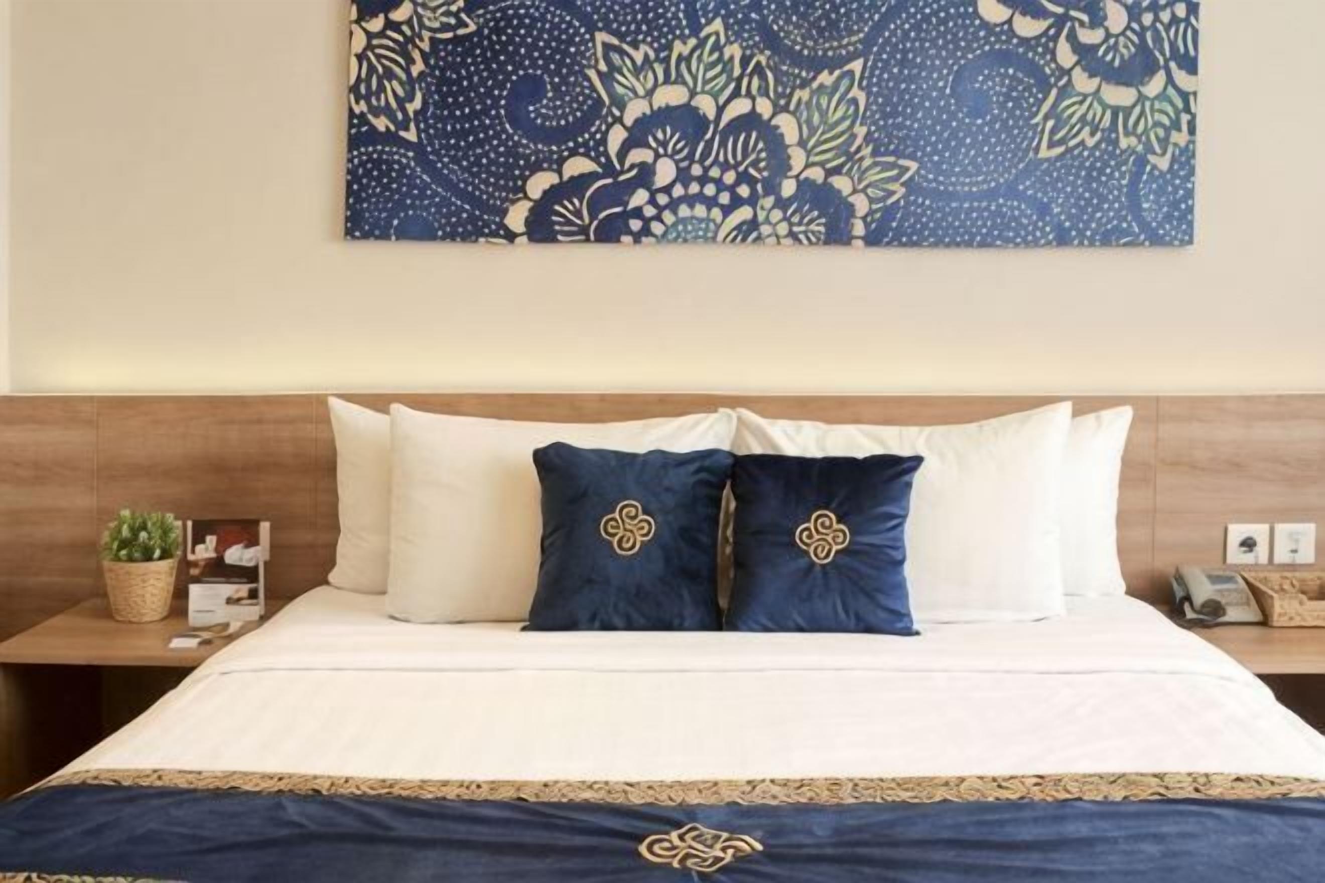 Une chambre d’hôtel avec un lit, des oreillers, une table de chevet et un élément décoratif mural.