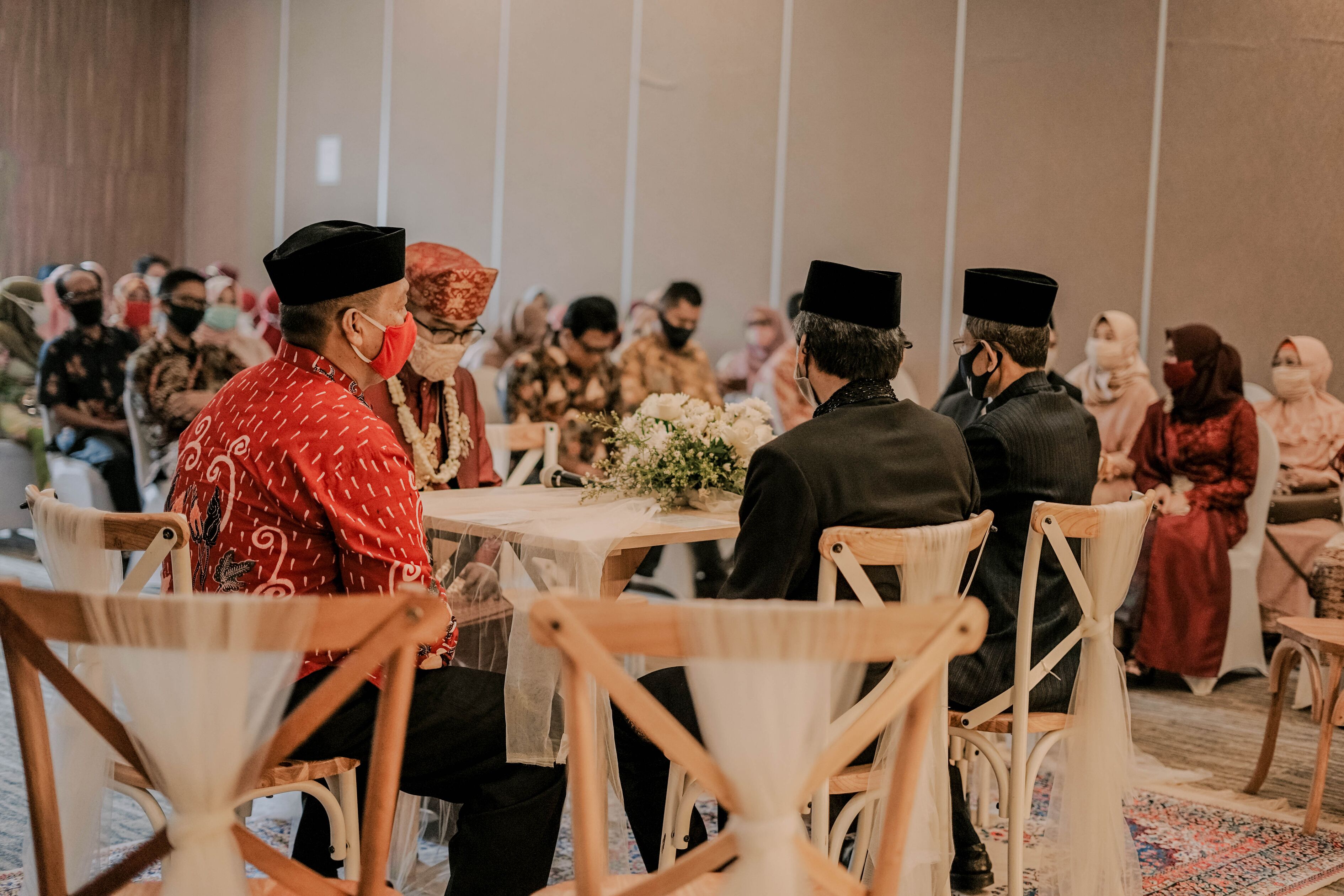 Evento formal con asistentes sentados en mesas redondas, algunos con atuendo tradicional.