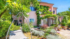 A garden with a swing chair, potted plants, and a building with a pink facade. - 2 bedroom cozy apartment in Krasica (Krasica)