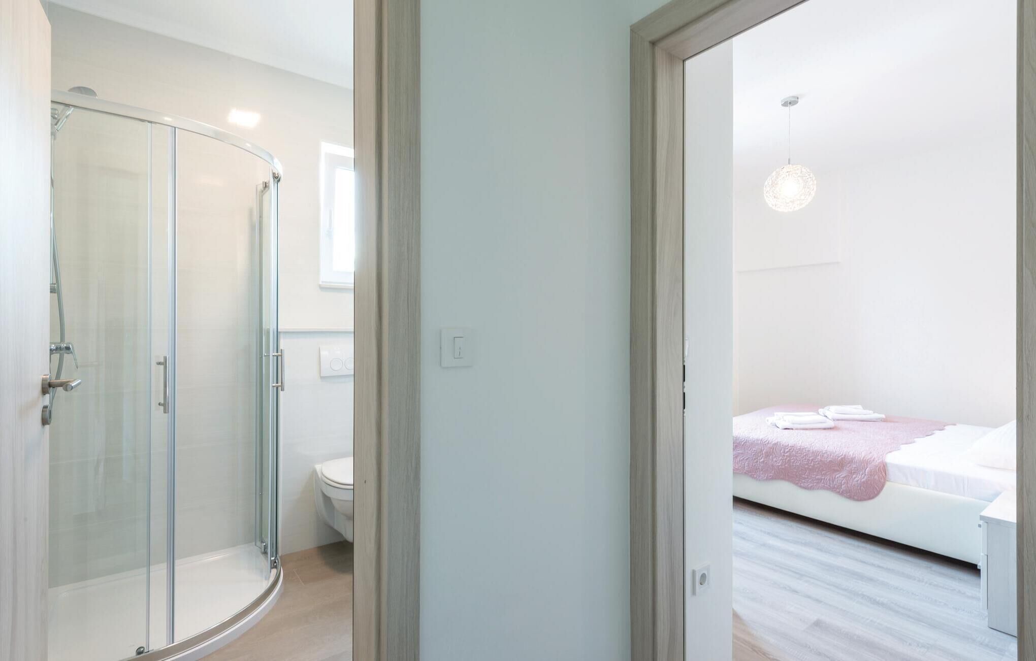 A modern bathroom with a glass shower enclosure and a toilet.