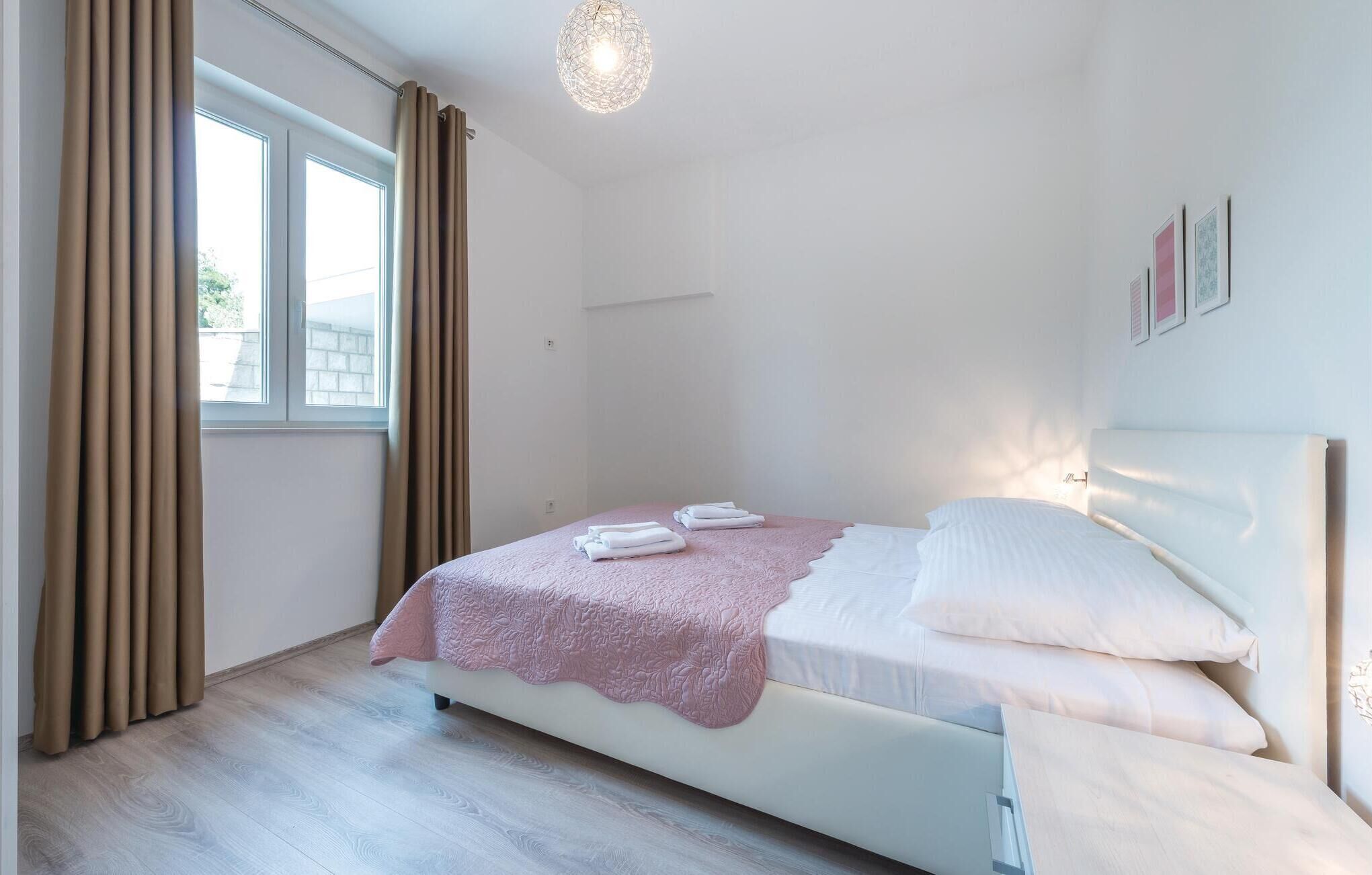 Un dormitorio con cama, una ventana con cortinas, una lámpara de pared y un pequeño marco de fotos.