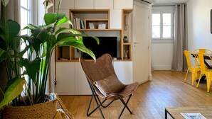 A living room with a brown leather chair, a television, and a bookshelf. - Les Toits de Sainte-Ursule (Montpellier)