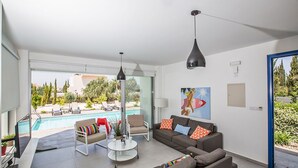 Un salon moderne avec vue sur la piscine, un ensemble de canapés et un coin repas.