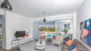 Un salon moderne avec un téléviseur, un canapé et une vue sur une piscine.