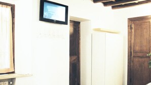 A room with a television mounted on the wall, a wooden door, and a white wardrobe. - Charming apartment in Navona Square (Multiple rentals available) (Roma)