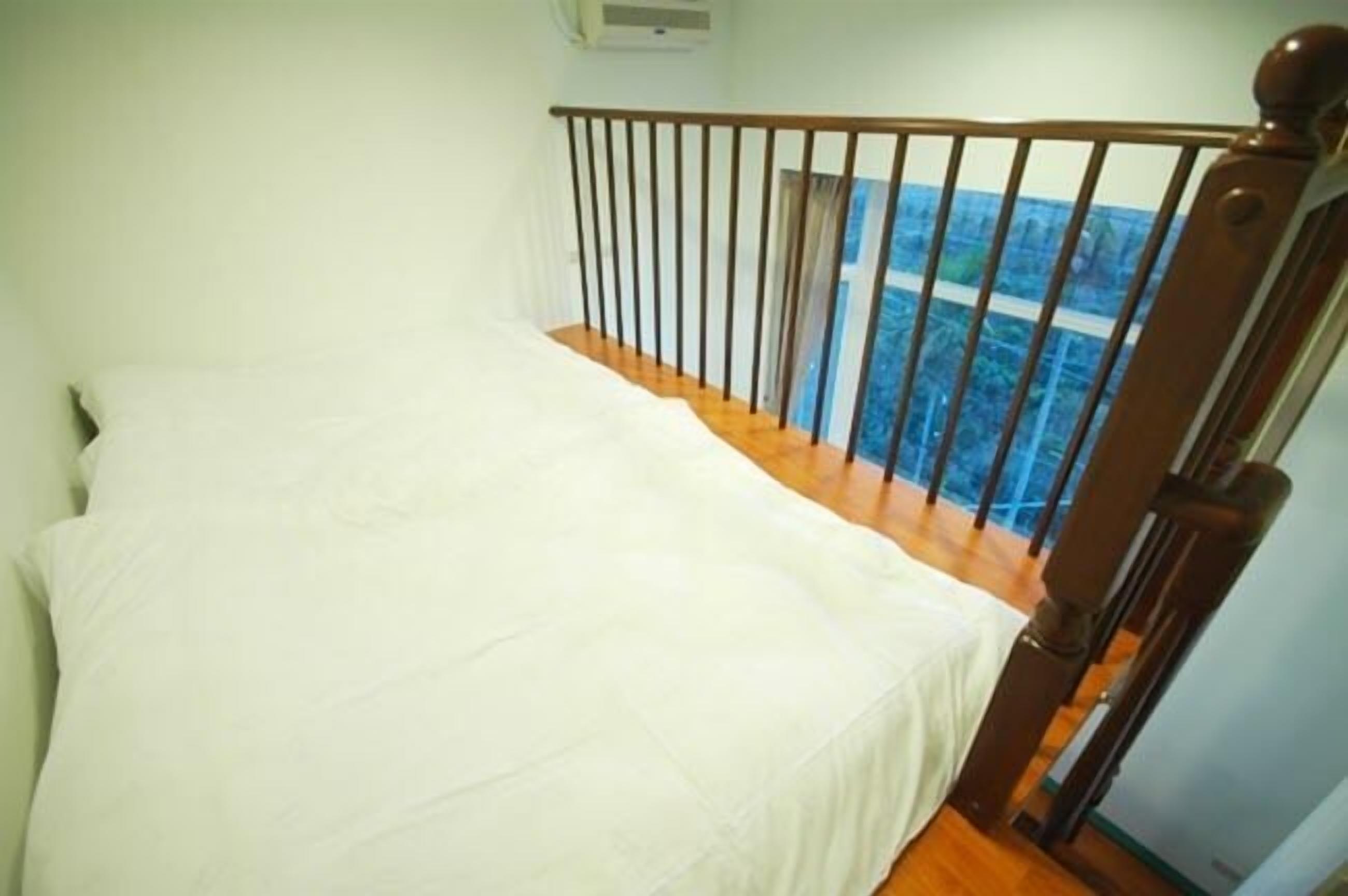 Een slaapkamer met een houten bed, een witte spreidek en een balkon met uitzicht op zee.