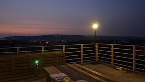 A rooftop terrace with a wooden table, a bench, and a street lamp. - Warm House Hostel (Taichung)
