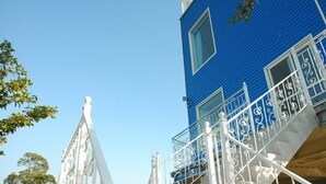 A blue building with a white balcony railing and a statue on the left. - Warm House Hostel (Taichung)