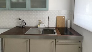 Une cuisine équipée d’un évier en acier inoxydable, d’une machine à café et d’une planche à découper pos ée sur le plan de travail.