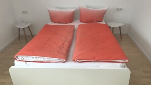 Un lit double avec deux oreillers et une couverture rouge.