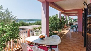 Un espace extérieur abrité avec une table et des chaises, une vue sur la mer et un balcon doté d’une balustrade.