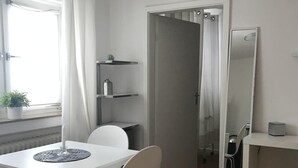 A modern, well-lit room with a dining table, chairs, a small shelf with decorative items, a mirror, and a radiator. - Small home in the spa area Freudenstadt (Freudenstadt)