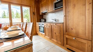 Eine Küche mit Holzausstattung, einem eingebauten Backofen und einem Fenster mit Blick auf einen Garten.