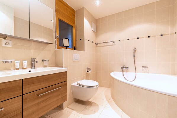 Une salle de bain moderne avec un lavabo blanc, un meuble-lavabo en bois, des toilettes et une baignoire sur pieds.