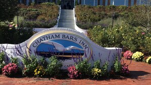 A sign for Chatham Bars Inn with a white building in the background.