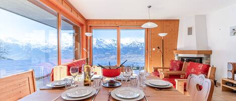 Mesa de madera para cuatro personas, con vistas a la montaña a través de amplios ventanales.