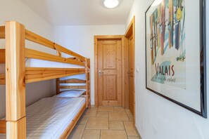 A room with bunk beds, a wooden door, and a framed picture on the wall.
