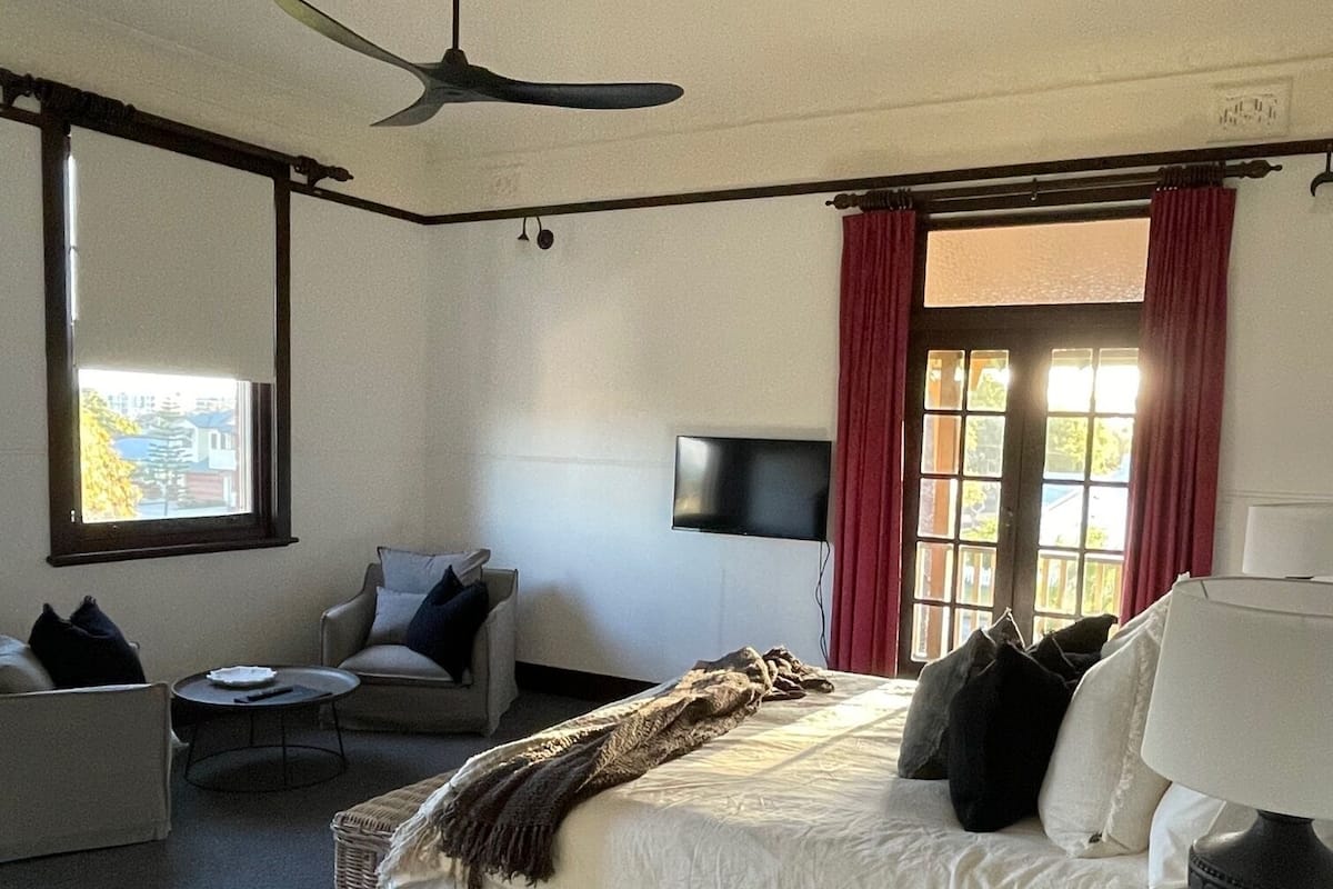 Ein Schlafzimmer mit einem Bett, einem Sessel, einem Fernseher und einem Deckenventilator.