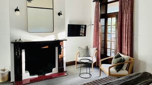 Een kamer met een open haard, een spiegel, een televisie en een raam met gordijnen.