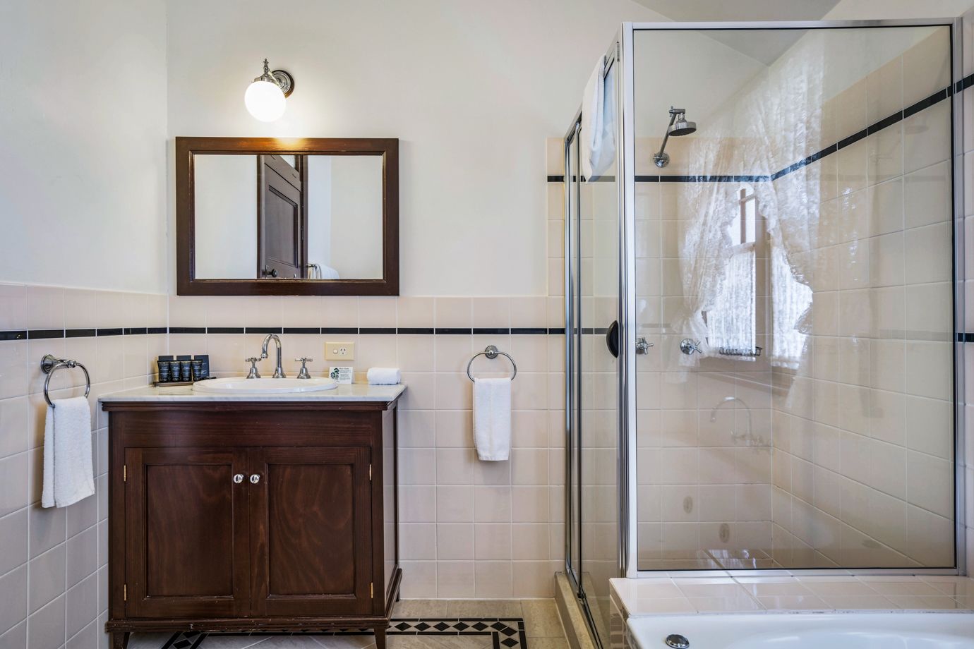 A modern bathroom with a wooden vanity, a glass shower enclosure, and a large mirror above the sink.