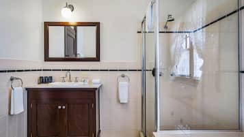 A modern bathroom with a wooden vanity, a glass shower enclosure, and a large mirror above the sink.