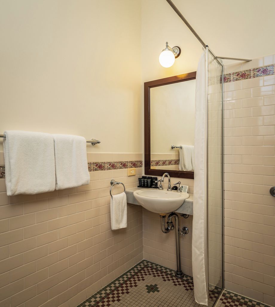 A bathroom with a sink, mirror, and shower.