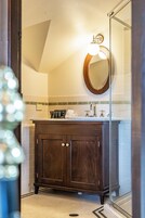 Un baño con tocador de madera, un espejo y cabina de ducha de vidrio.