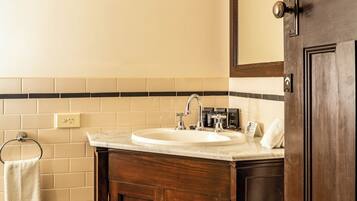 A bathroom with a wooden vanity, a white sink, and a mirror.