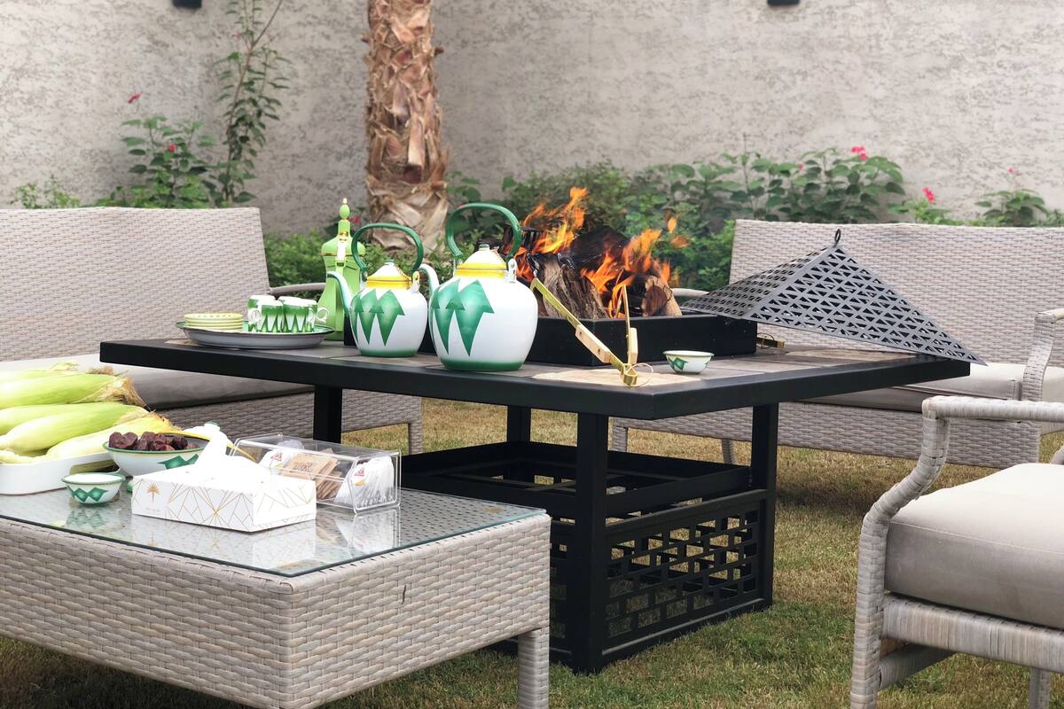 An outdoor seating area with wicker furniture, a glass-top table, and a fire pit.