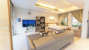 Una habitació d'hotel moderna amb un llit gran, un sofà, una televisió i una biblioteca.