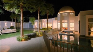 Un edifici modern amb piscina, palmeres i una estructura en forma de cúpula.