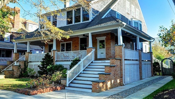 A two-story house with a front porch, a garage, and a staircase leading to the entrance. - Fully updated, 2 Blocks from the Beach, Sleeps 12 (Cape May)