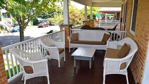 A covered porch with wicker furniture, including a sofa and chairs, and a small table. - Fully updated, 2 Blocks from the Beach, Sleeps 12 (Cape May)