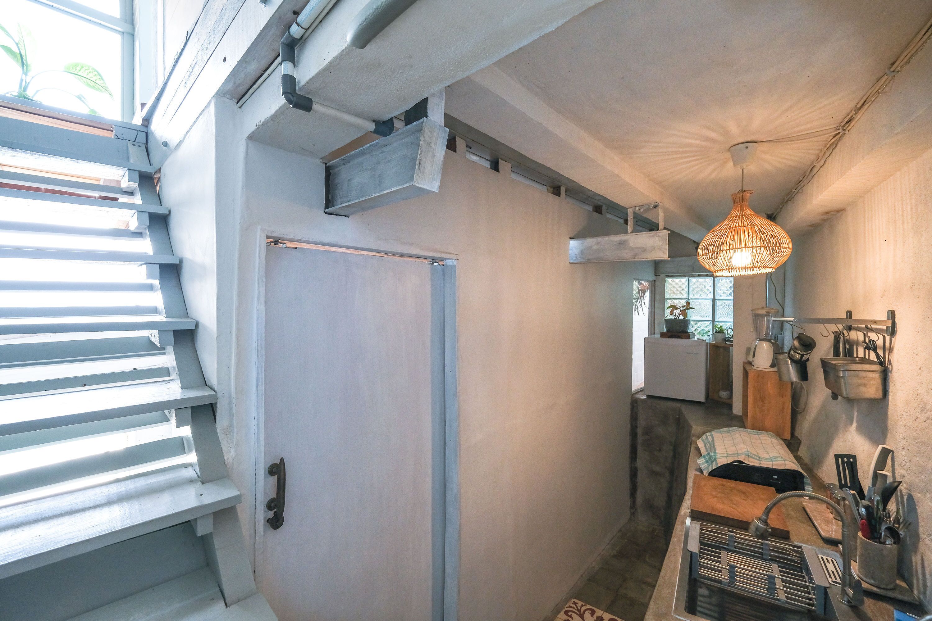 A compact kitchen with a built-in oven, a sink, and a hanging light fixture.